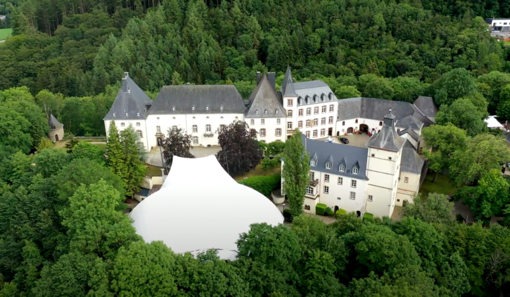 Aerial perspective of Campus Wiltz in Luxembourg, adorned with lush greenery and a canopy of trees, offering a serene and natural environment